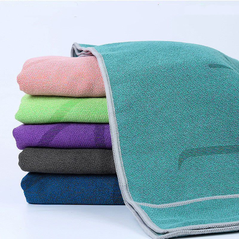 Stack of folded microfiber pilates towels in teal, pink, green, purple, grey, and blue