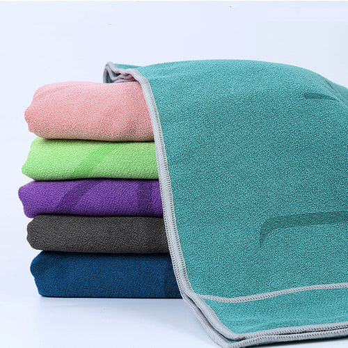 Stack of folded microfiber pilates towels in teal, pink, green, purple, grey, and blue