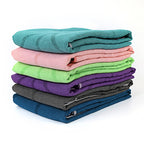 Folded microfiber pilates towels stacked in teal, pink, green, purple, grey, and blue